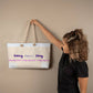 Weekender tote bag, happiness, with cream-colored rope handle and woman holding it to a wall - Sheer: your Luck - Sheerluck-art.com